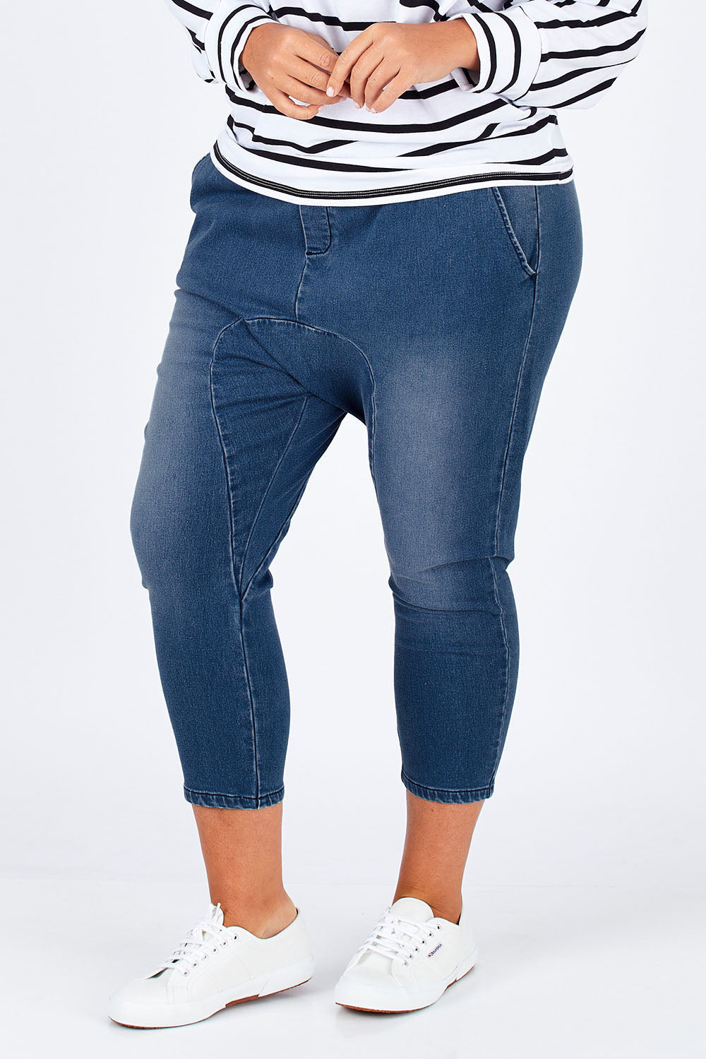 Model Fiona wearing size 16 of the Just Chillin Stretch Dropped Crotch Jeans in colour Denim (Blue), from the front, cropped image