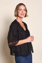 Model Riinar wearing size 10 of the Spring Day Cotton Throw - Black in colour Black, from an angle