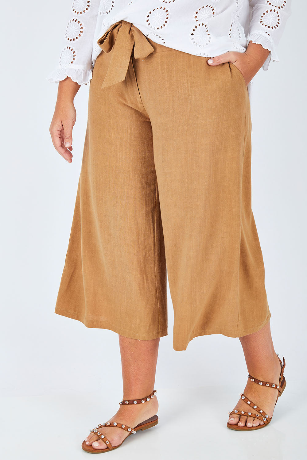 Model Fiona wearing size 16 of the Coyote Wide Leg Linen Blend Pant in colour Camel, from the front, cropped image