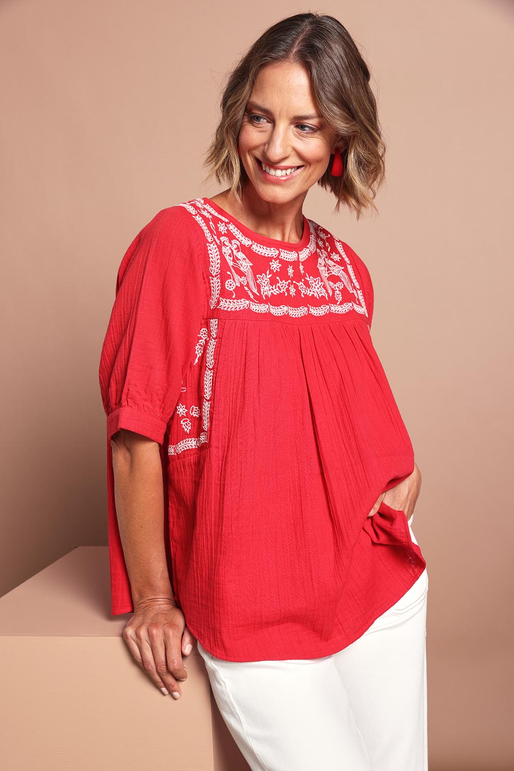Model Riina wearing size 10 of the Secret Garden Cotton Blouse in colour Scarlet (Red), from the front, cropped image