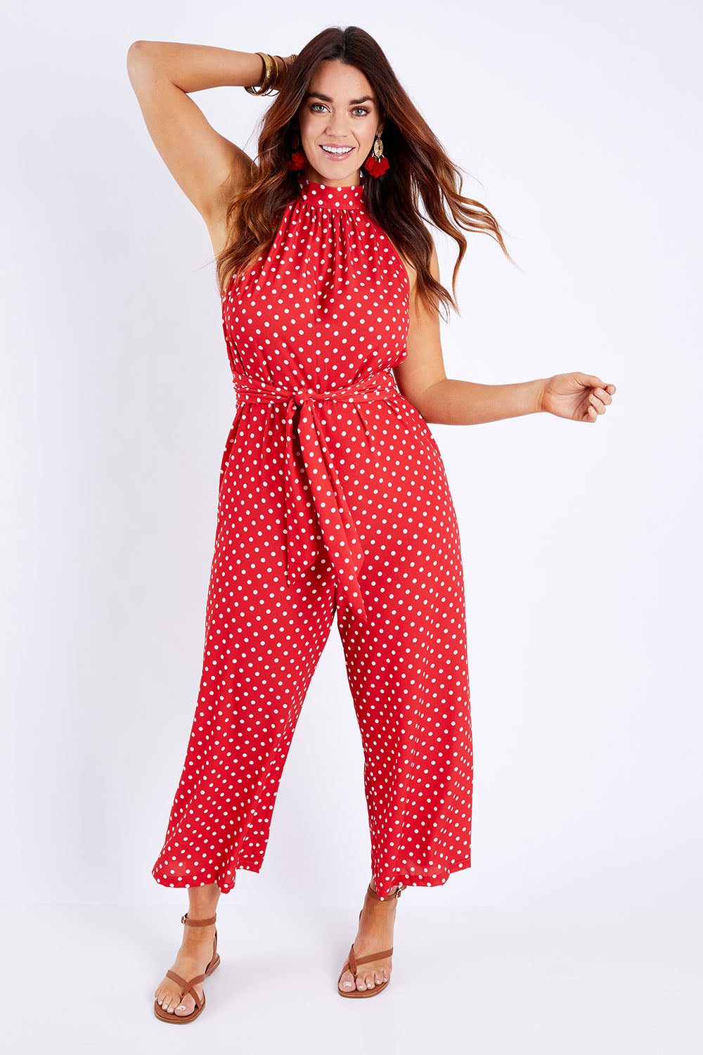 Model Laura wearing size 14 of the Lets Get Festive Jumpsuit in colour Redspot (Red), from the front, showing the whole outfit