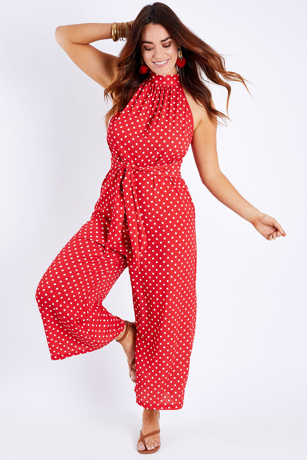 Model Laura wearing size 14 of the Lets Get Festive Jumpsuit in colour Redspot (Red), from the front, showing the whole outfit