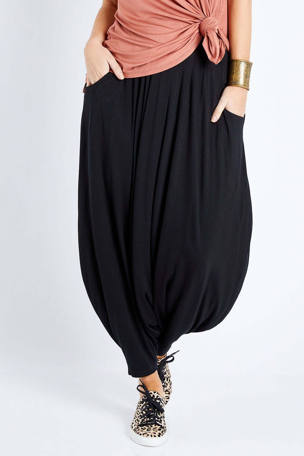 Model Laura wearing size 12 of the Softly Swinging Bamboo Harem Pants in colour Black (Black), from the front, cropped image