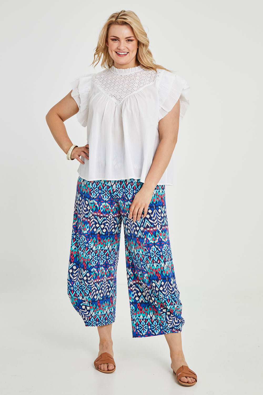 Model Keeara wearing size 16 of the Good Vibes Balloon Hem Pants in colour Aztec (Blue), from the front, showing the whole outfit
