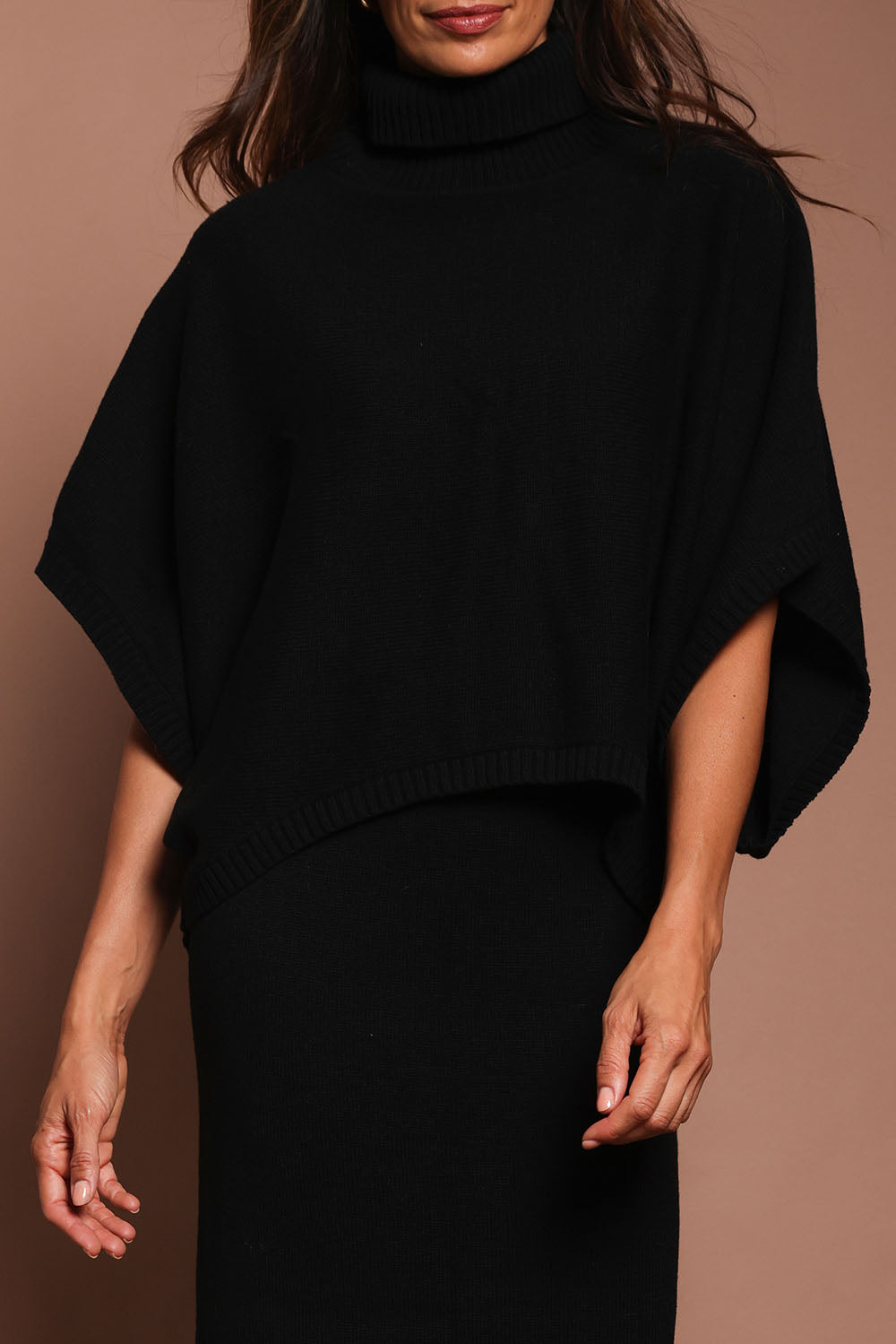 Model Amanda wearing size S of the Knit Pick Throw Sweater in colour Black (Black), from the front, cropped image