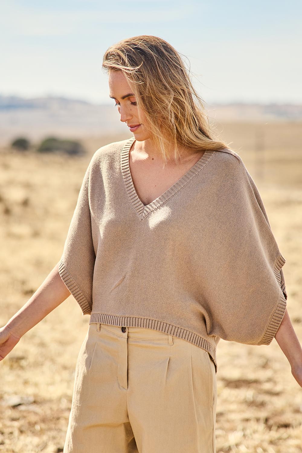Model Tegan wearing size S of the Knit Pick Throw V Neck Sweater in colour Latte, from the front, showing the whole outfit