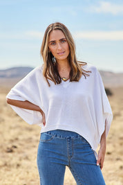Model Tegan wearing size S of the Knit Pick Throw V Neck Sweater in colour Milk (White), from the front, showing the whole outfit