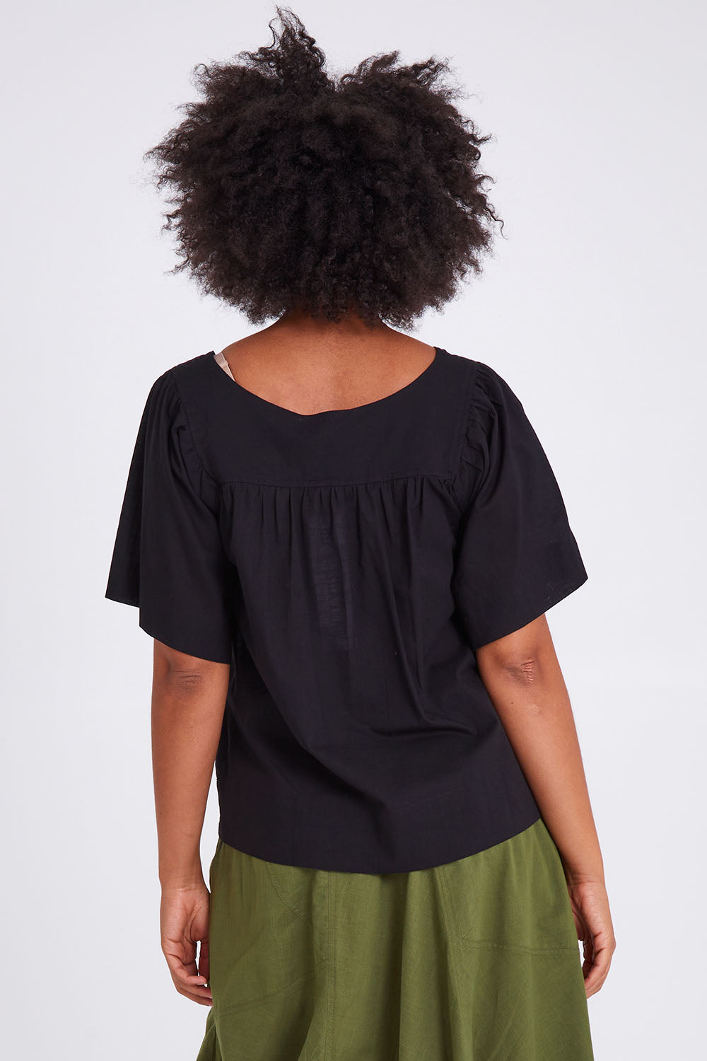 Model Olivia wearing size 10 of the Freya Top in colour Black (Black), from the back