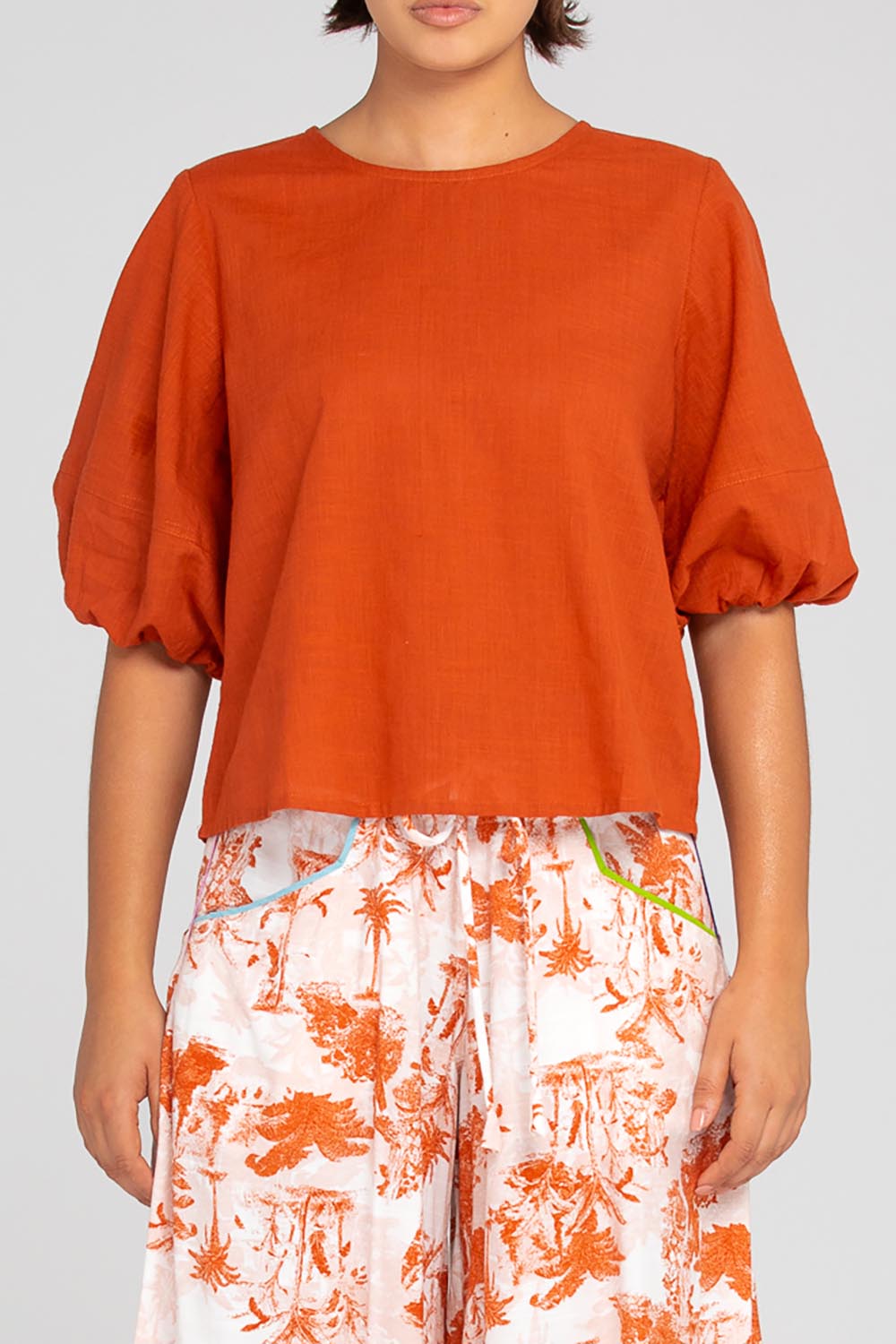 A model wearing the Ava Cotton Top in colour Mecca, from the front, cropped image