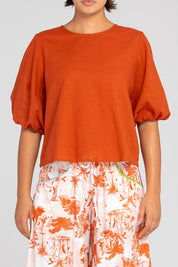 A model wearing the Ava Cotton Top in colour Mecca, from the front, cropped image