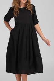 A model wearing the Guru Cotton Dress in colour Black (Black), from the front, cropped image