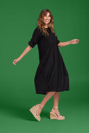 A model wearing the Guru Cotton Dress in colour Black (Black), from the front, showing the whole outfit