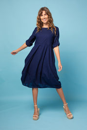 A model wearing the Guru Cotton Dress in colour Navy (Blue), from the front, showing the whole outfit