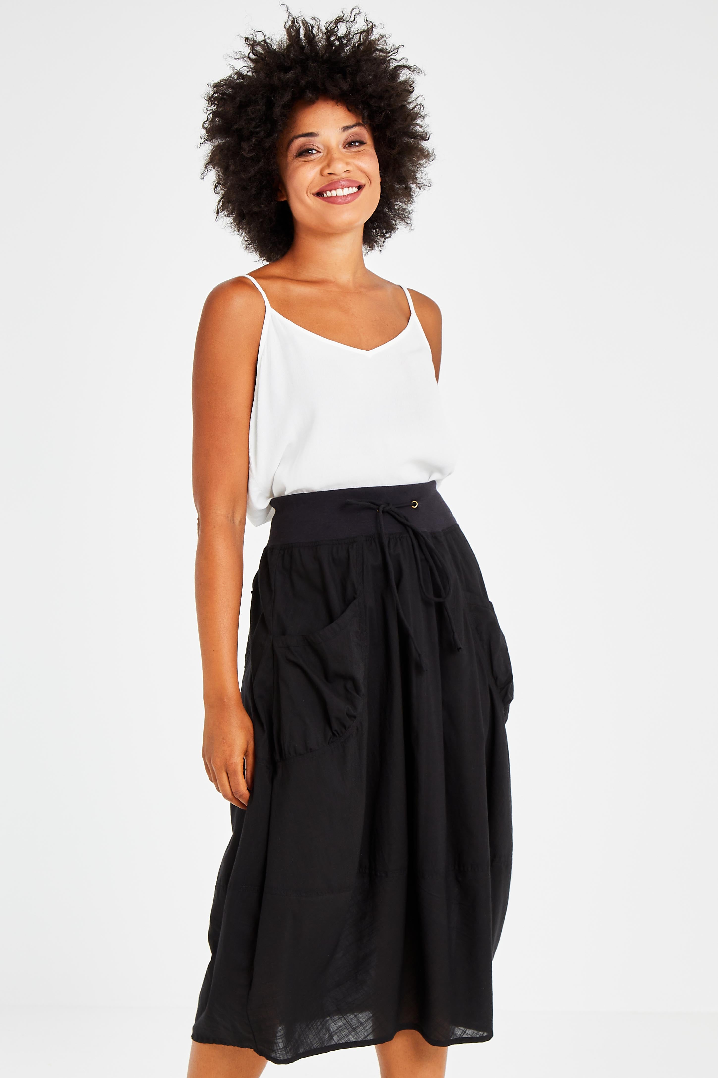Model Olivia wearing size 10 of the Guru Skirt in colour Black (Black), from the front, cropped image
