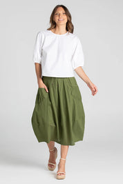 A model wearing the Guru Skirt in colour Khaki (Green), from the front, cropped image