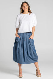 A model wearing the Guru Skirt in colour Chambray (Blue), from the front, showing the whole outfit