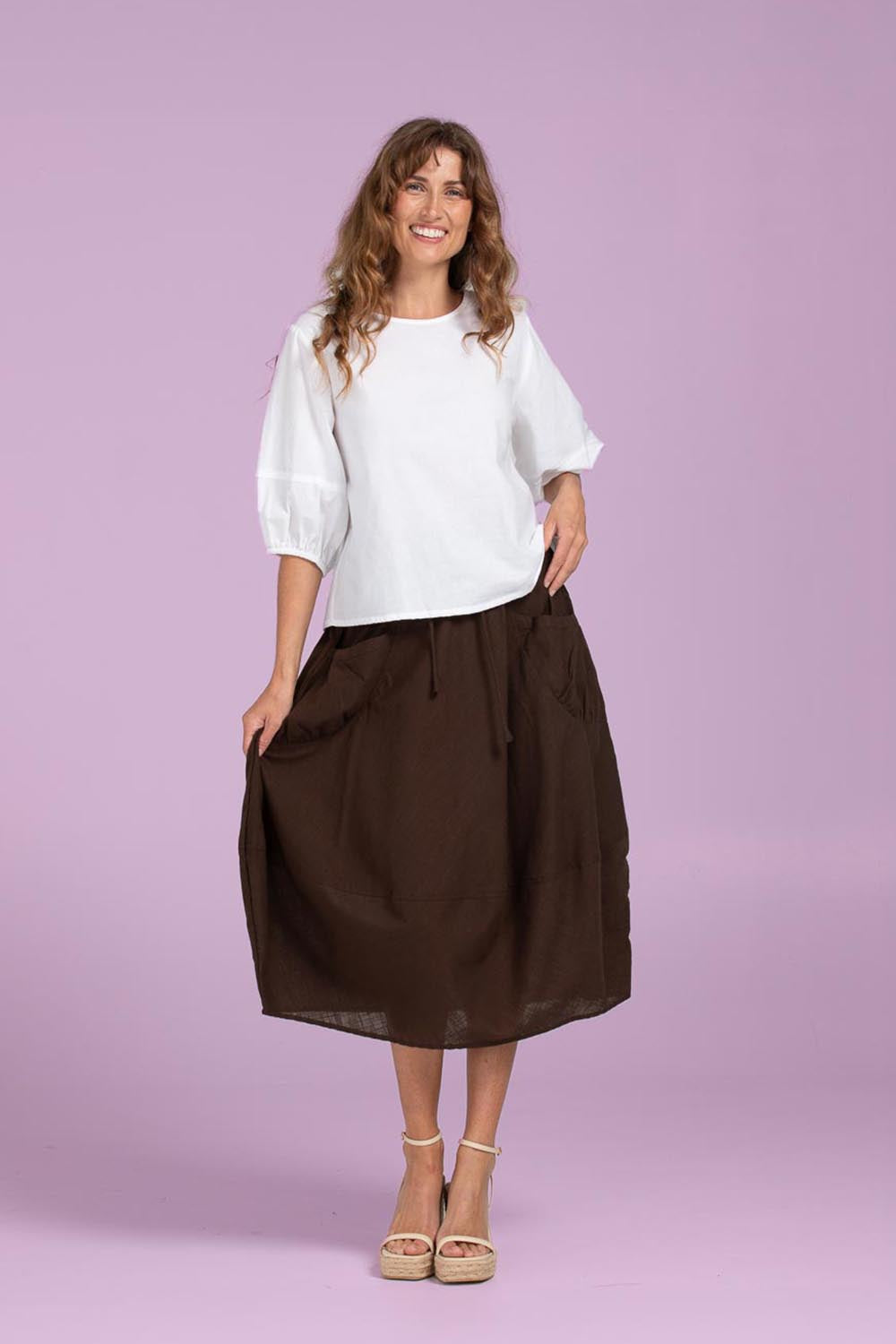 A model wearing the Guru Cotton Skirt in colour Coffee, from the front, showing the whole outfit
