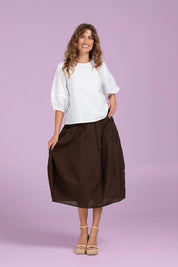 A model wearing the Guru Cotton Skirt in colour Coffee, from the front, showing the whole outfit