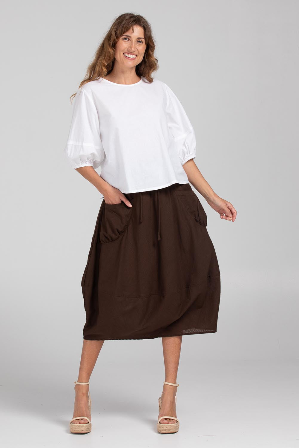 A model wearing the Guru Cotton Skirt in colour Coffee, from the front, showing the whole outfit