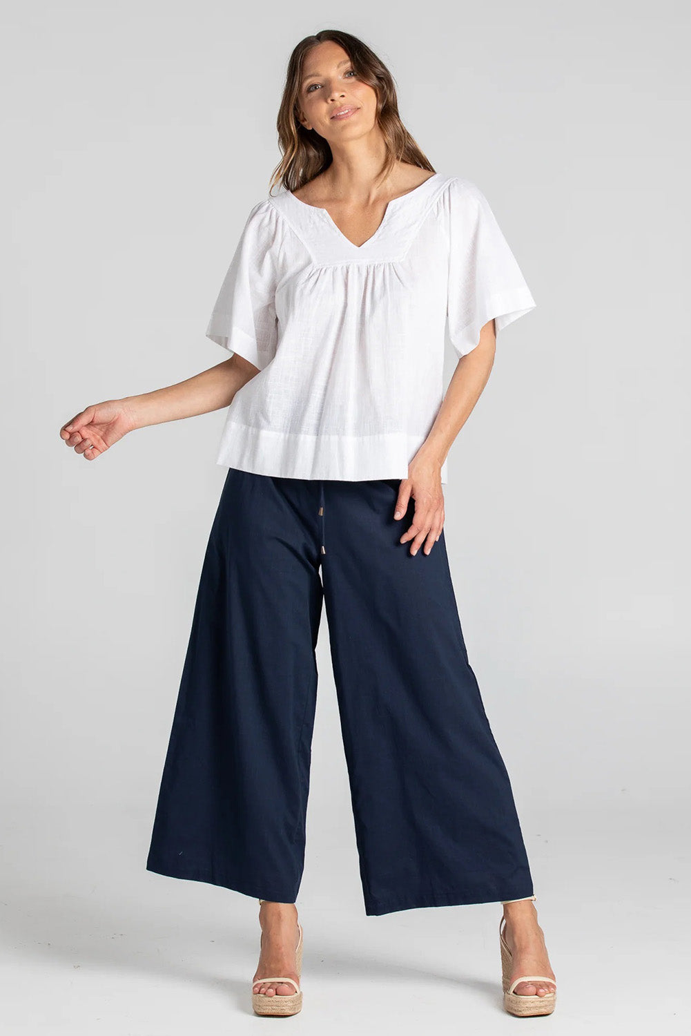A model wearing the Ria Pant in colour Navy (Blue), from the front, showing the whole outfit