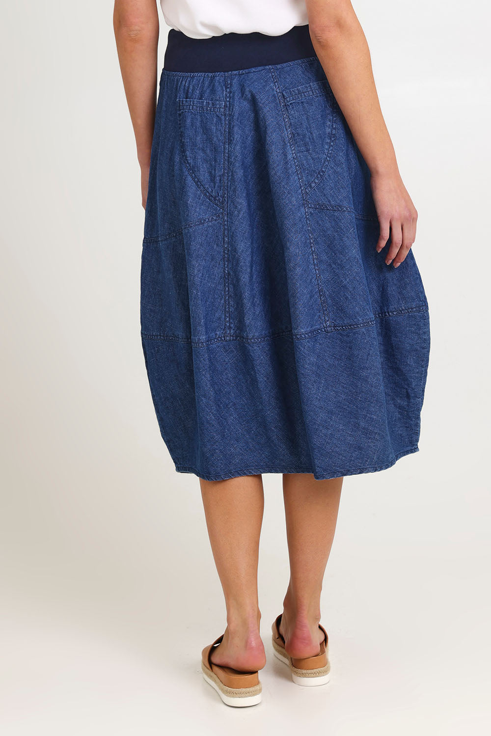 Model Madeline wearing size 10 of the Guru Denim Skirt in colour Middenim (Blue), from the back