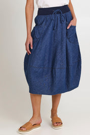 Model Madeline wearing size 10 of the Guru Denim Skirt in colour Middenim (Blue), from the front, cropped image