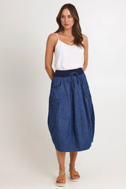 Model Madeline wearing size 10 of the Guru Denim Skirt in colour Middenim (Blue), from the front, showing the whole outfit