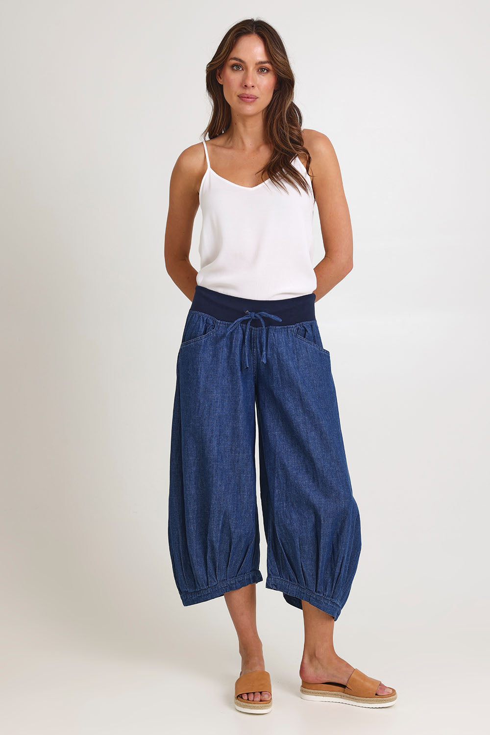 Model Madeline wearing size 10 of the Guru Denim Pant in colour Middenim (Blue), from the front, showing the whole outfit