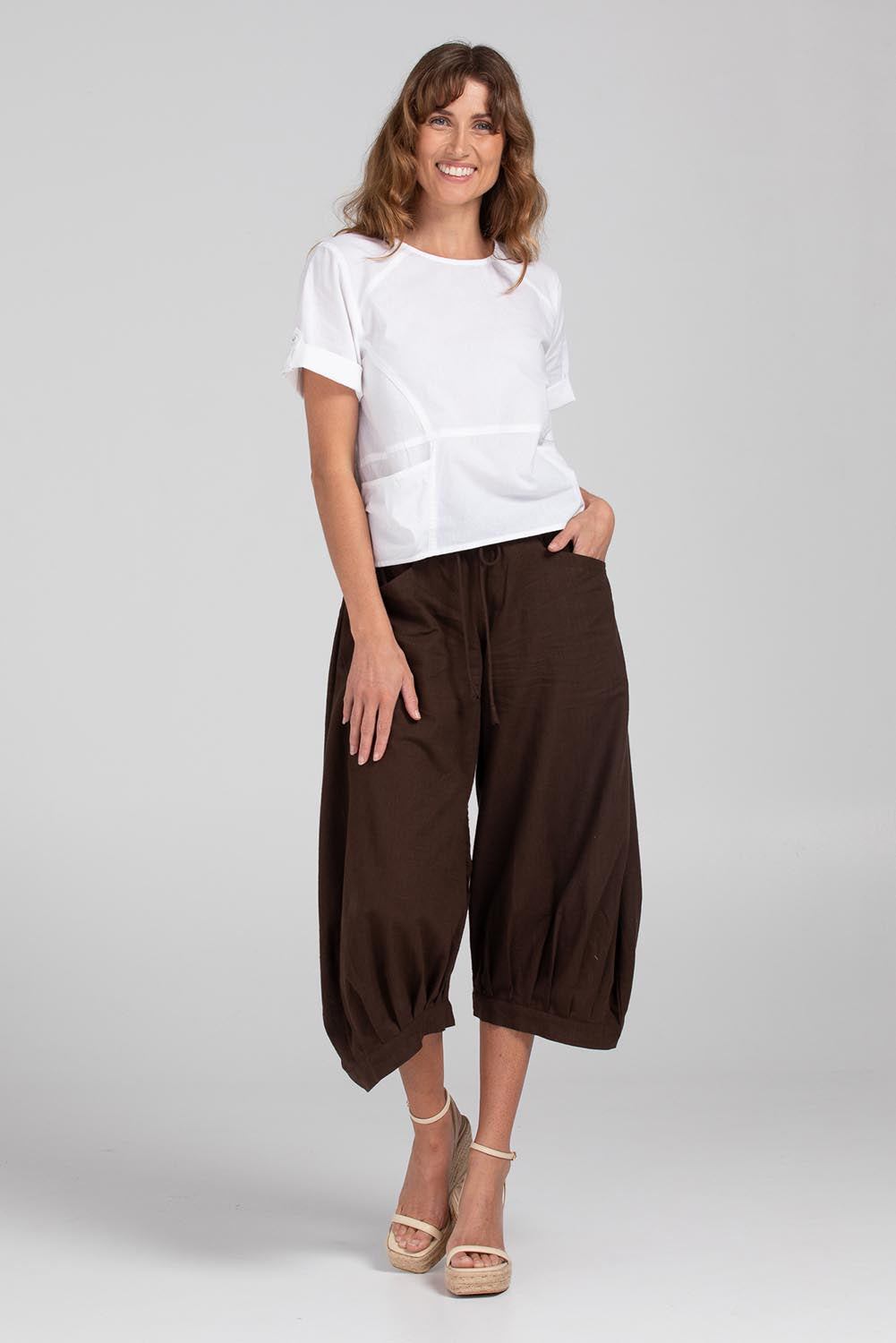 A model wearing the Guru Pant in colour Coffee, from the front, showing the whole outfit