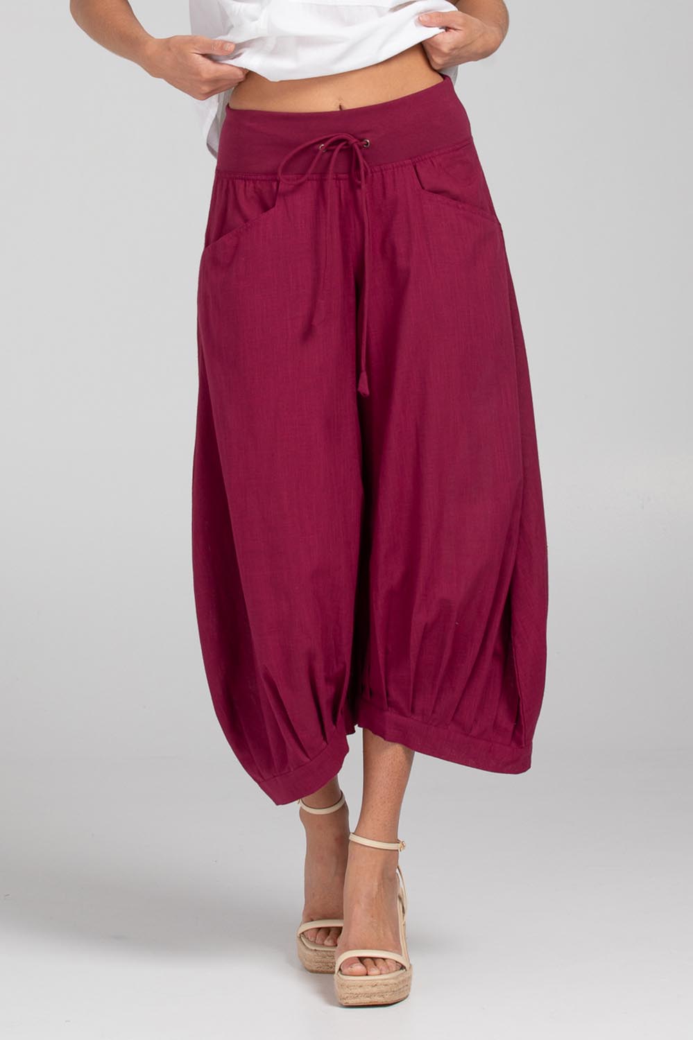 A model wearing the Guru Pant in colour Magenta (Purple), from the front, cropped image