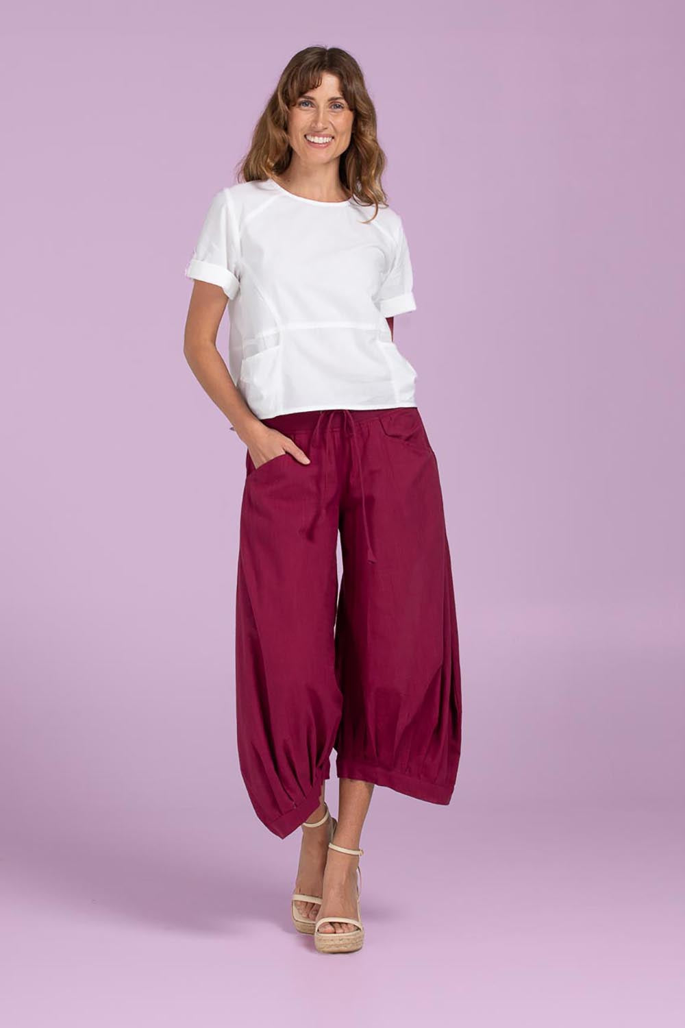 A model wearing the Guru Pant in colour Magenta (Purple), from the front, showing the whole outfit
