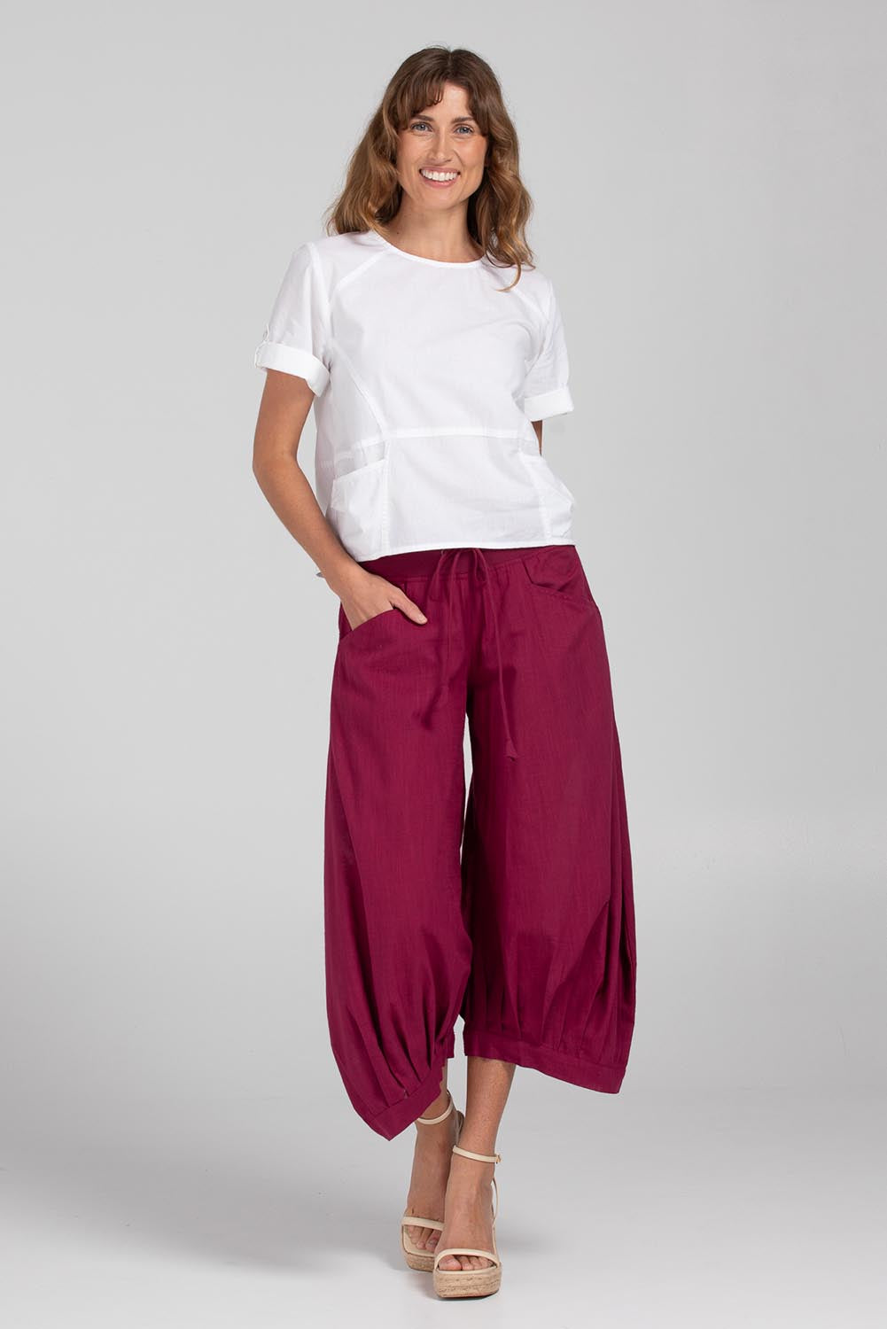 A model wearing the Guru Pant in colour Magenta (Purple), from the front, showing the whole outfit