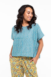 A model wearing the Alora Top in colour Bananaflow (Blue), from the front, cropped image
