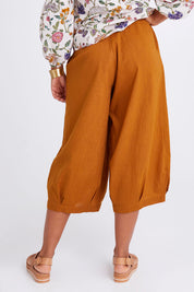 Model Olivia wearing size 10 of the Zetta Pant in colour Mustard, from the back