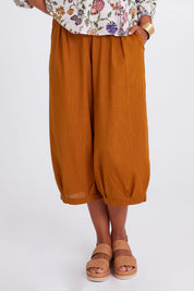 Model Olivia wearing size 10 of the Zetta Pant in colour Mustard, from the front, cropped image