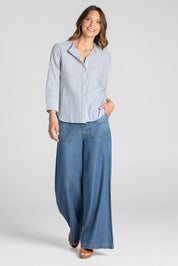 A model wearing the Hazel Shirt in colour Hazelstrip (Blue), from the front, showing the whole outfit