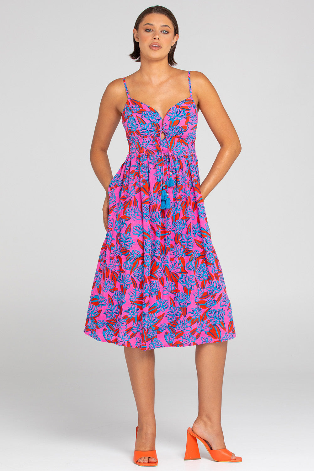 A model wearing the Ailana Dress in colour Ray (Pink), from the front, showing the whole outfit