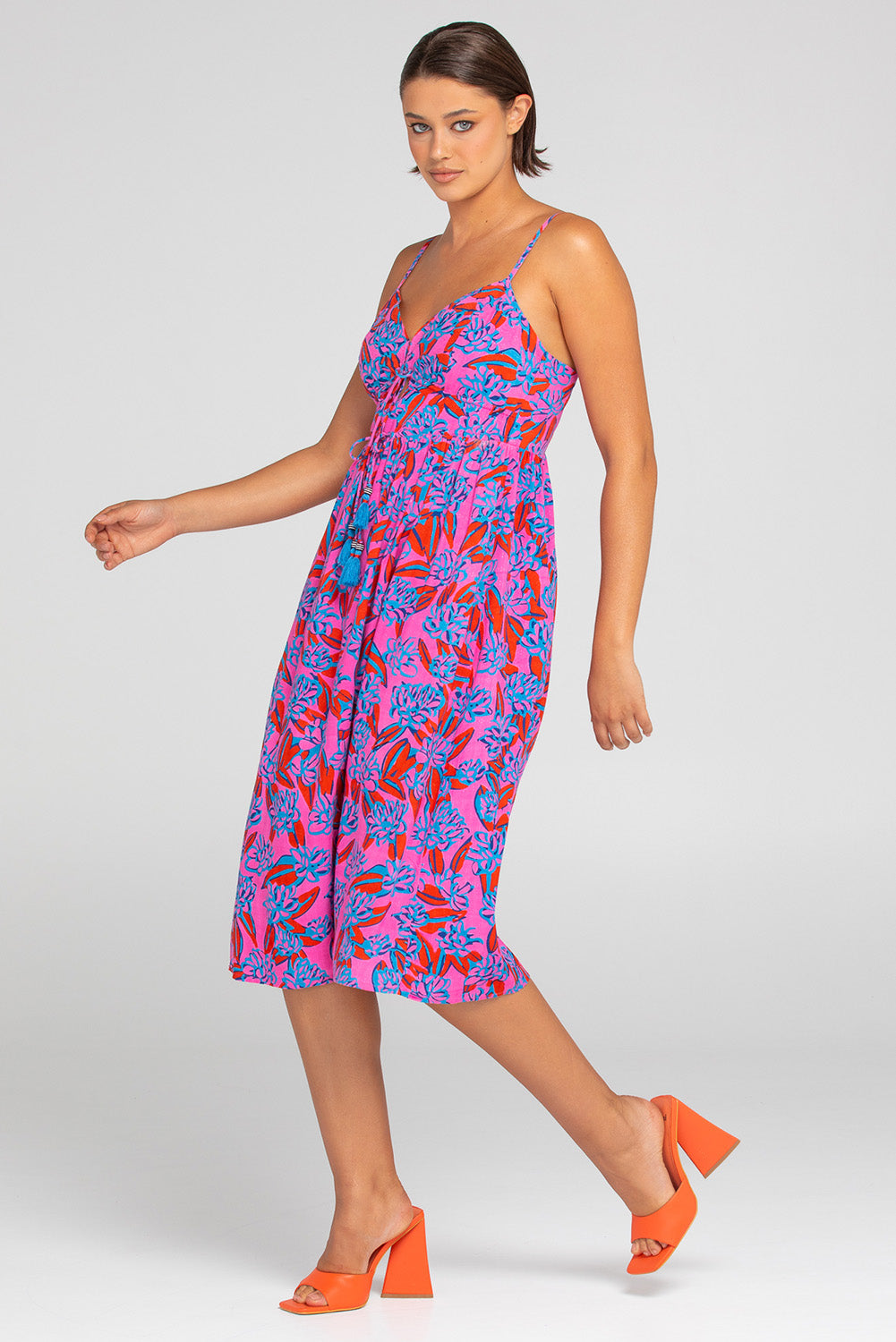 A model wearing the Ailana Dress in colour Ray (Pink), from the front, showing the whole outfit