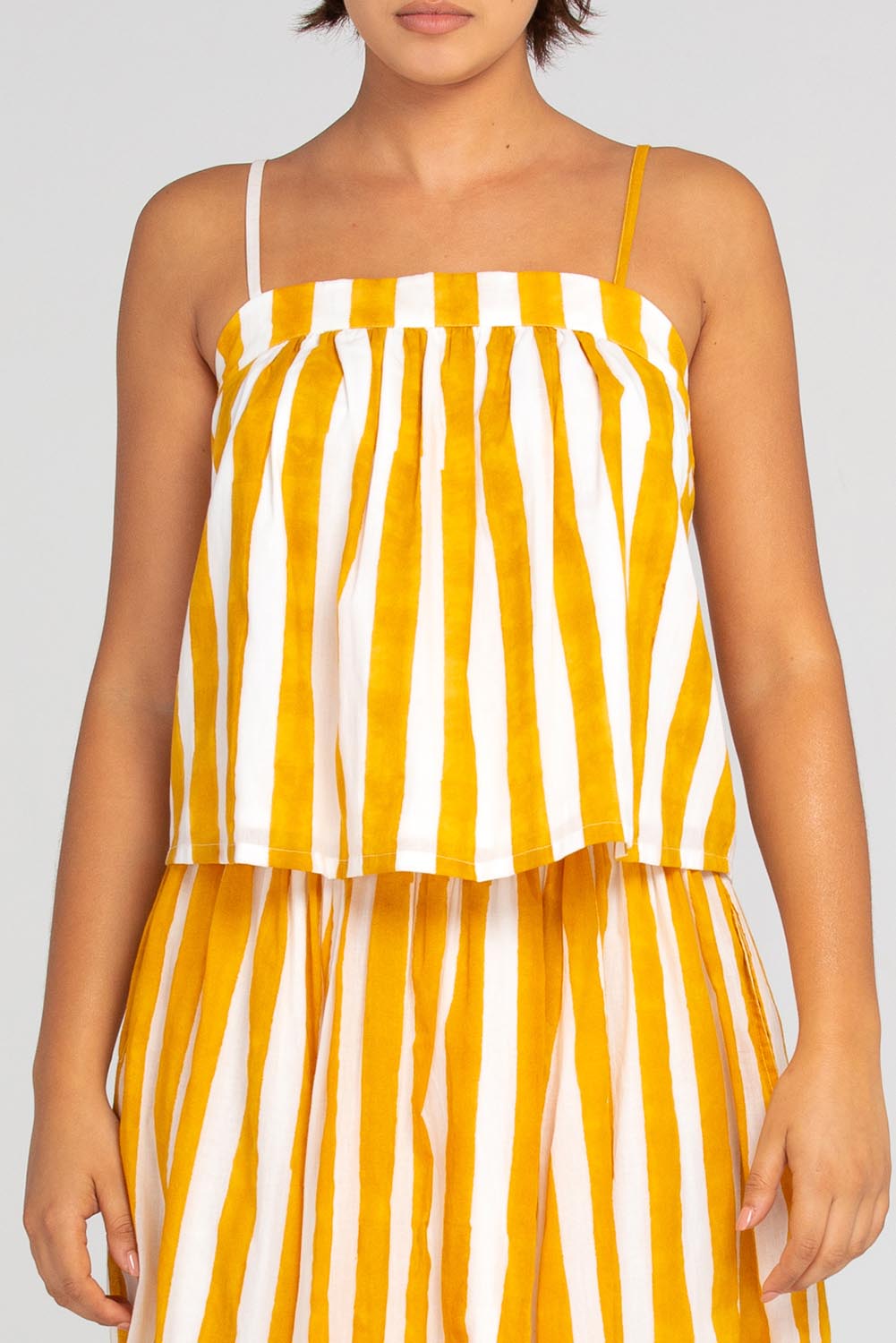 A model wearing the Sami Cotton Singlet in colour Tropical, from the front, cropped image