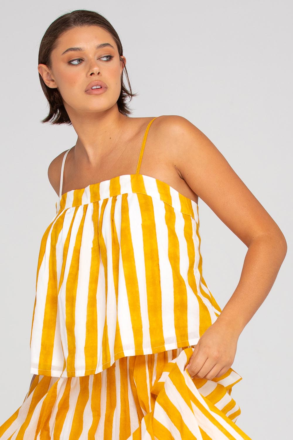 A model wearing the Sami Cotton Singlet in colour Tropical, from the front, cropped image