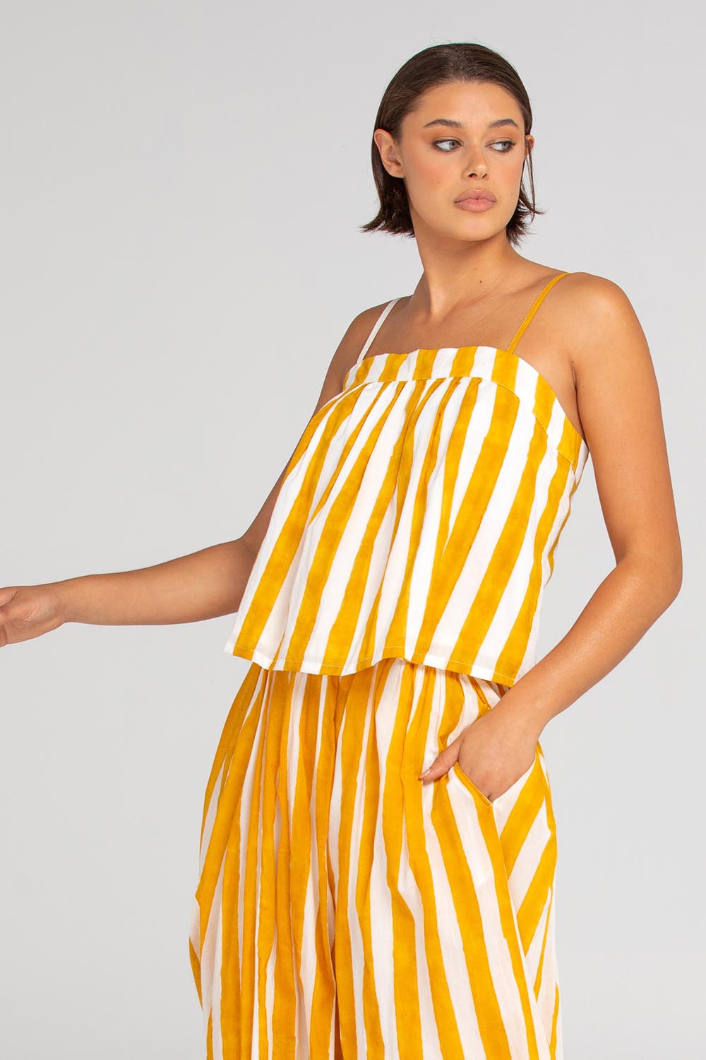A model wearing the Sami Cotton Singlet in colour Tropical, from the front, cropped image