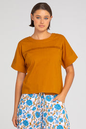 A model wearing the Haven Cotton Top in colour Mustard, from the front, cropped image