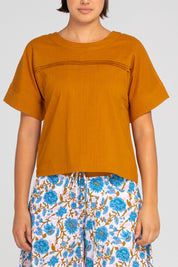 A model wearing the Haven Cotton Top in colour Mustard, from the front, cropped image