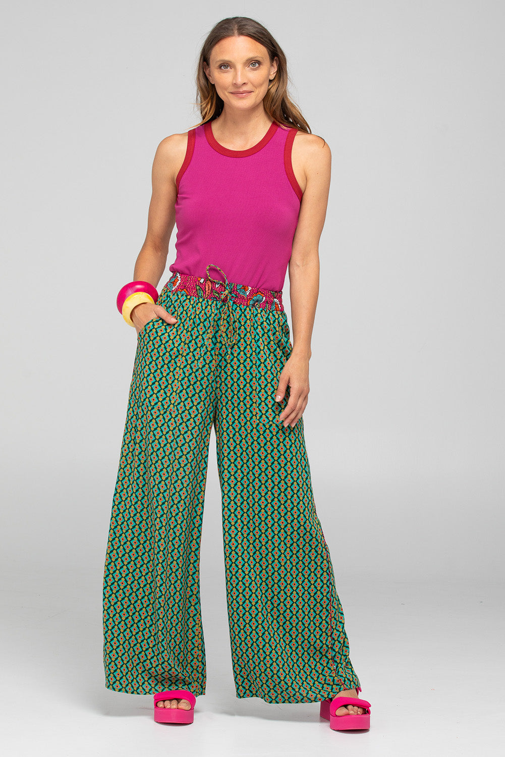 A model wearing the Harper Pant in colour Celaya (Green), from the front, showing the whole outfit