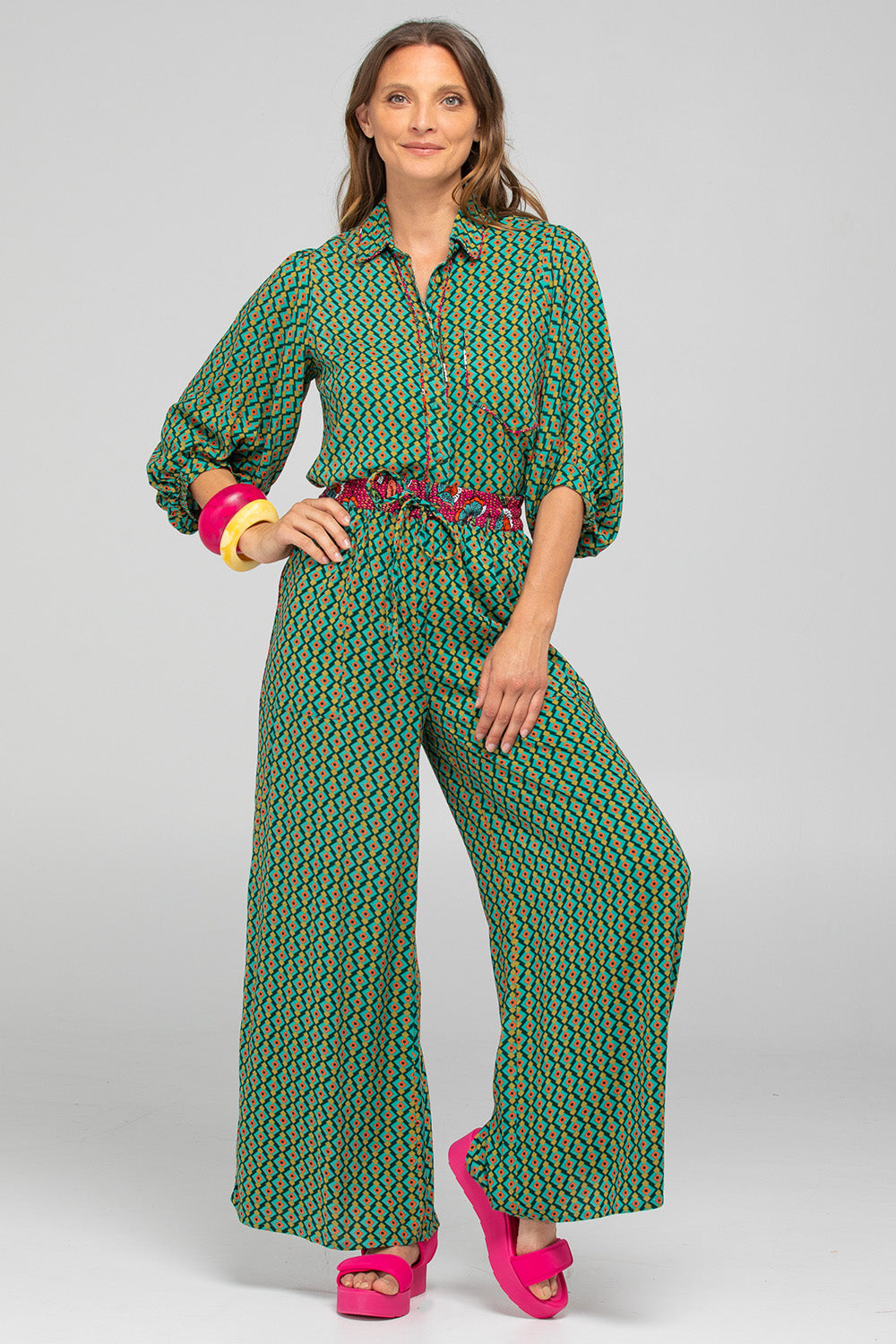 A model wearing the Harper Pant in colour Celaya (Green), from the front, showing the whole outfit