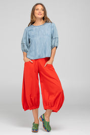 A model wearing the Guru Cotton Pant in colour Pomodoro (Red), from the front, showing the whole outfit