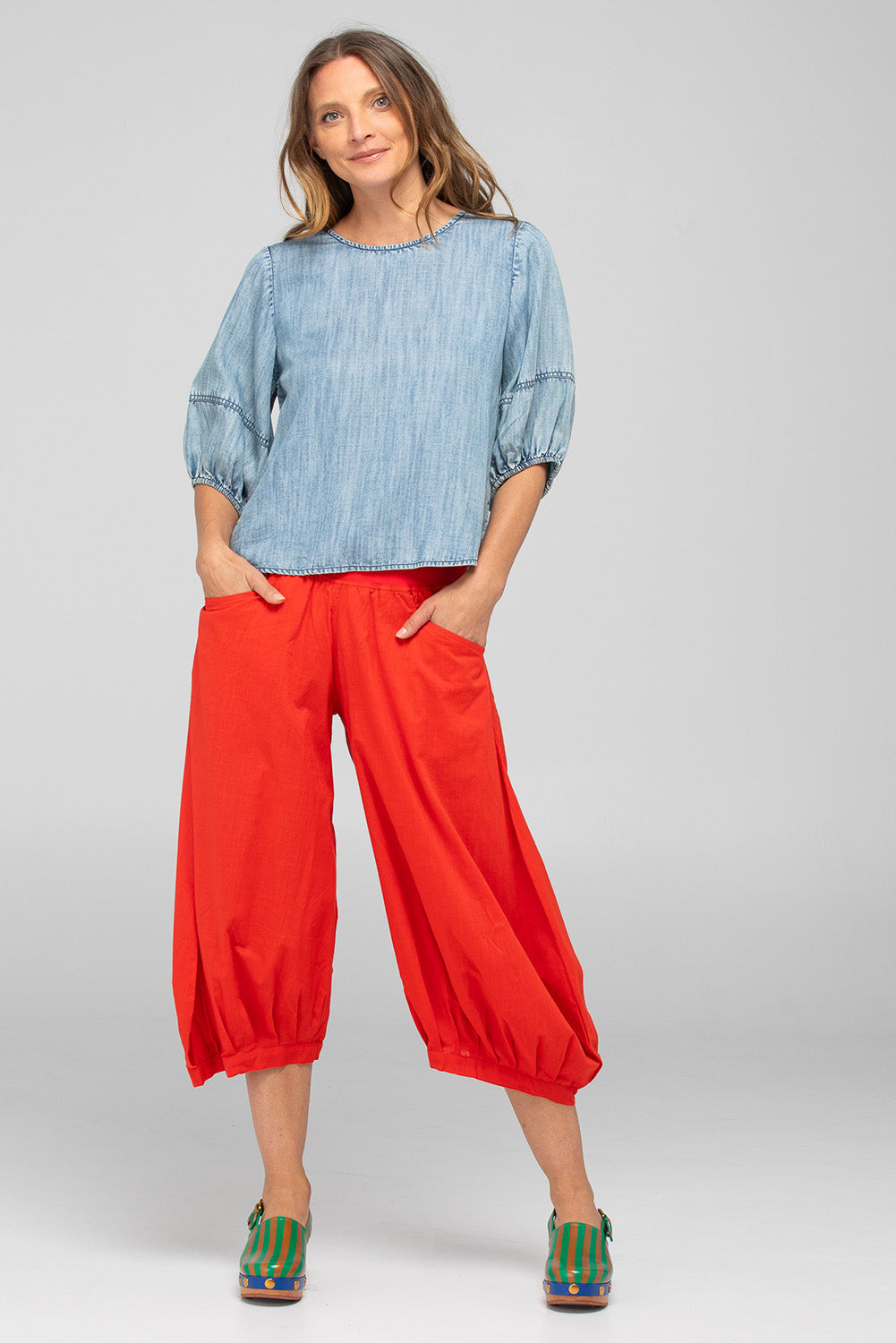 A model wearing the Guru Cotton Pant in colour Pomodoro (Red), from the front, showing the whole outfit