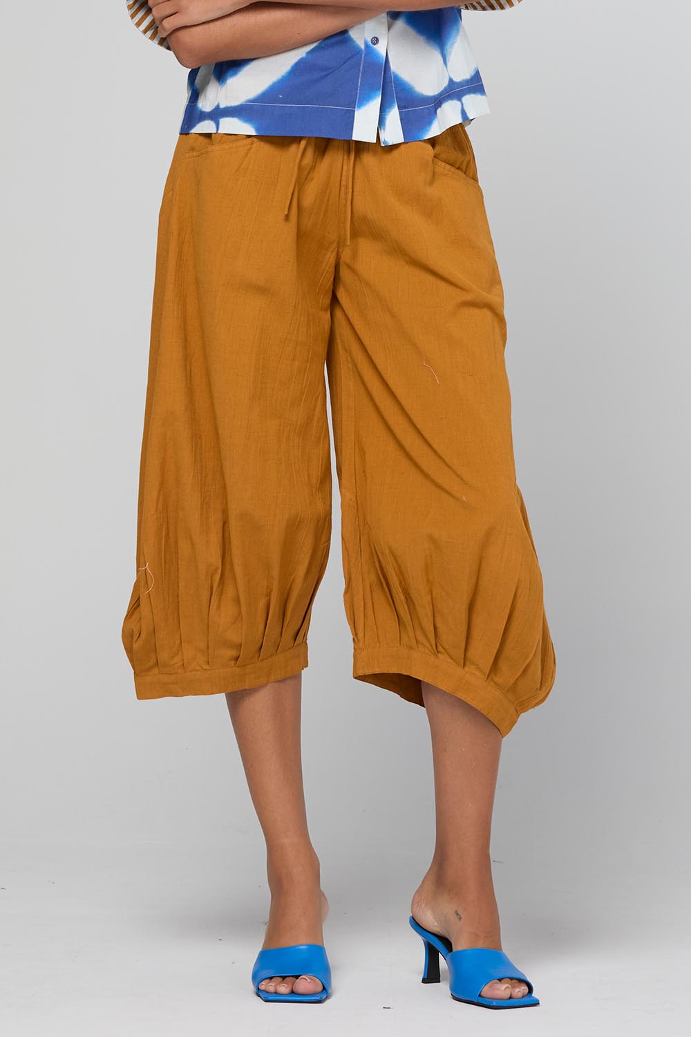 Model Genericm wearing size sample of the Guru Pant – Turmeric in colour Turmeric, in a cropped view