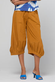 Model Genericm wearing size sample of the Guru Pant – Turmeric in colour Turmeric, in a cropped view