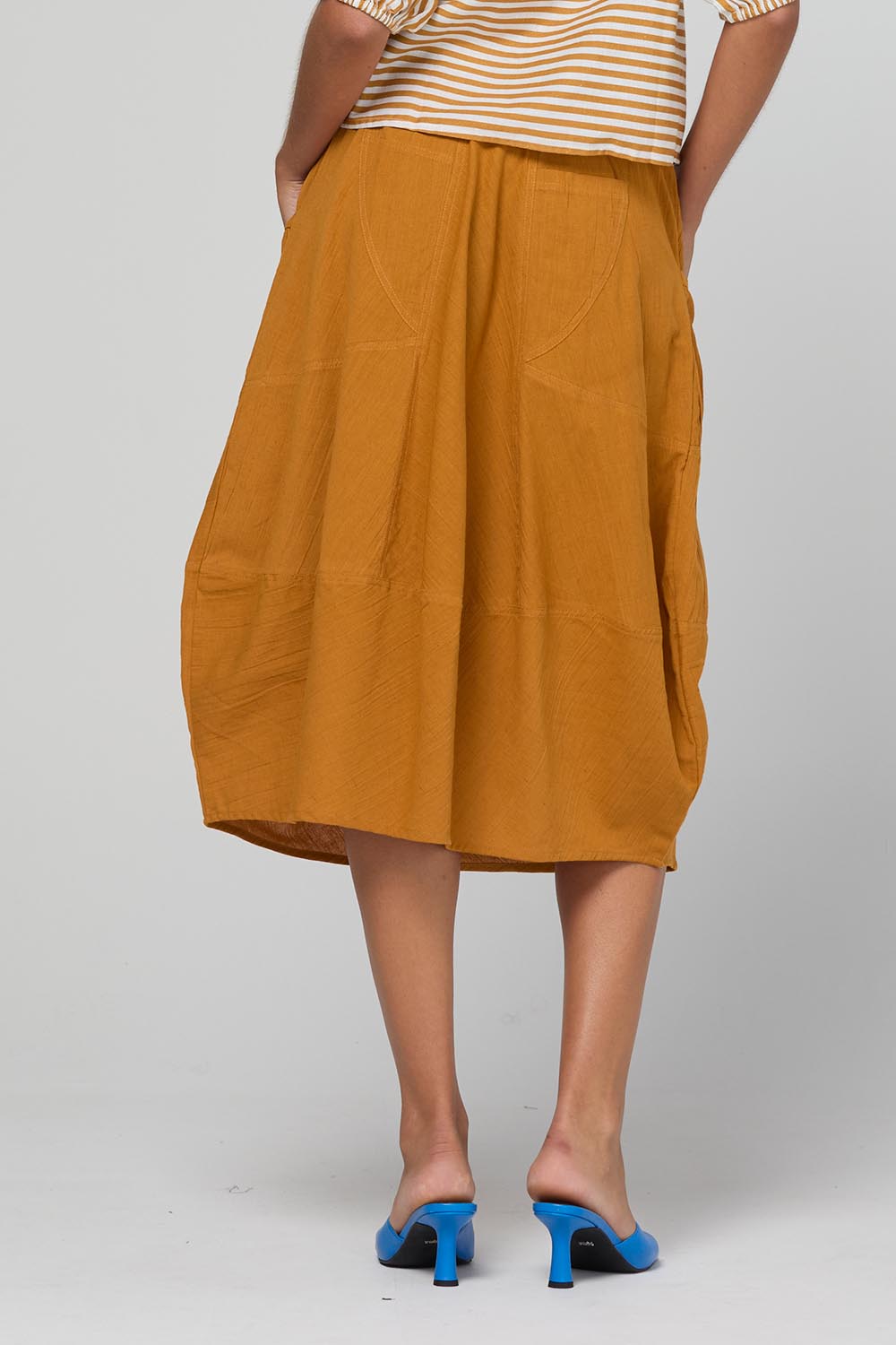 Model Genericm wearing size sample of the Guru Skirt – Turmeric in colour Turmeric, from the back